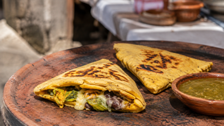 Itacates tradicionales recién cocidos sobre un comal de barro, acompañados de salsa verde
